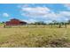 View of a home and barn from across a large field at 8703 Alafia Hills Dr, Plant City, FL 33567