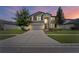 Two-story house with gray siding, stone accents, and a three-car garage at dusk at 19065 Malinche Loop, Spring Hill, FL 34610