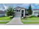 Two-story house with gray siding, stone accents, and a three car garage at 19065 Malinche Loop, Spring Hill, FL 34610