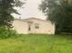 Rear view of a white single story home with overgrown yard at 1908 51St W Ave, Bradenton, FL 34207
