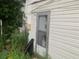 Side view of a white single story home with overgrown yard and exterior door at 1908 51St W Ave, Bradenton, FL 34207