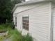 Side view of a white single story home with overgrown yard at 1908 51St W Ave, Bradenton, FL 34207