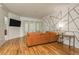 Bright living room with orange sectional sofa, wood floors, and geometric accent wall at 5047 Silver Charm Ter, Wesley Chapel, FL 33544