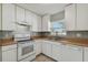 Bright kitchen with white cabinets, appliances, and light brown countertops at 6824 N Sterling Ave, Tampa, FL 33614