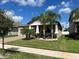 Tan house with beige garage door, landscaping, and palm trees at 13240 Satin Lily Dr, Riverview, FL 33579