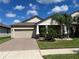 Tan house with beige garage door, landscaping, and palm trees at 13240 Satin Lily Dr, Riverview, FL 33579
