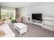 Bright living room featuring comfy seating, a large TV, and access to a patio at 1450 Heather Ridge Blvd # 107, Dunedin, FL 34698