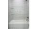 Bright bathroom featuring a tub with marble look tile walls and glass shelving at 11452 81St Pl, Seminole, FL 33772