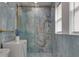 Stunning bathroom featuring blue marble-style tile, gold fixtures, and a modern glass shower at 11452 81St Pl, Seminole, FL 33772