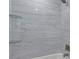 Bright bathroom featuring a tub with marble look tile walls and glass shelving at 11452 81St Pl, Seminole, FL 33772