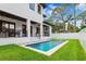 Backyard with a pool, lush grass, a modern white home with black trim, and a patio with furniture at 4625 W El Prado Blvd, Tampa, FL 33629