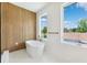 Bright bathroom featuring a soaking tub, wood accent wall, contemporary fixtures, and natural light from two windows at 4625 W El Prado Blvd, Tampa, FL 33629