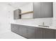 This laundry room features gray cabinets, a white countertop, stainless steel sink, and a white backsplash at 4625 W El Prado Blvd, Tampa, FL 33629