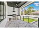 Outdoor kitchen with stainless steel grill, sink, mini fridge, dark granite counters and a black ceiling fan at 4625 W El Prado Blvd, Tampa, FL 33629