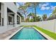 Backyard showcasing a pool, grass, and the side of a modern white house with black trim at 4625 W El Prado Blvd, Tampa, FL 33629