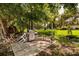 Outdoor grilling area with a gas grill, chairs, and a bench under the trees at 12300 Vonn Rd # 7101, Largo, FL 33774