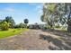 Single wide manufactured home with a gravel driveway and lush landscaping at 11109 Sumner Rd, Wimauma, FL 33598