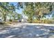 Gravel driveway leads to a home nestled amongst mature trees with Spanish moss at 11109 Sumner Rd, Wimauma, FL 33598