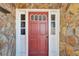Inviting red front door with sidelights, set against a stone facade at 11109 Sumner Rd, Wimauma, FL 33598