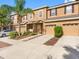 Exterior view of townhomes featuring two-car garages, neutral paint, and well-maintained landscaping at 12820 Belvedere Song Way, Riverview, FL 33578