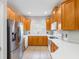 Open-concept kitchen featuring stainless steel appliances, wooden cabinets, and bar overlooking the living room at 12820 Belvedere Song Way, Riverview, FL 33578