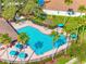 Aerial view of a community pool surrounded by palm trees, lounge chairs, and tables with umbrellas at 12820 Belvedere Song Way, Riverview, FL 33578