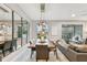 Modern dining room with a long wooden table, gray chairs, and a view into the living room at 10012 Corso Milano Dr, Tampa, FL 33625