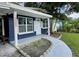 Front entrance of a charming home with a navy blue exterior and landscaped walkway at 10007 N 22Nd St, Tampa, FL 33612