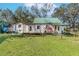 A charming home with a green roof, a manicured lawn, and mature landscaping at 10824 Palmetto St, Riverview, FL 33569