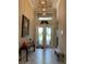 Bright foyer with decorative glass double-doors, chandelier, and travertine floors at 16015 Cape Coral Dr, Wimauma, FL 33598
