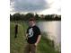 Personal holding a fishing pole with a fish on the line standing near the water and wearing an Avengers T-shirt at 16015 Cape Coral Dr, Wimauma, FL 33598