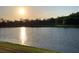 Picturesque sunset view over the lake with calm water and lush green trees in the background at 16015 Cape Coral Dr, Wimauma, FL 33598