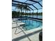 A beautiful screened-in pool with clear blue water and views of the lake and palm trees in the backyard at 16015 Cape Coral Dr, Wimauma, FL 33598