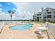 View of pool, palm tree, lounge furniture, and building with covered patios at the community complex at 3127 W Sligh Ave # 204B, Tampa, FL 33614