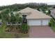 Two-story home with tile roof, three-car garage, and landscaped yard at 16015 Cape Coral Dr, Wimauma, FL 33598