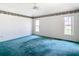 Spacious bedroom with teal carpet, ceiling fan, and multiple windows at 11111 Dormie Dr, San Antonio, FL 33576