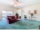 Spacious living room with teal carpet, a maroon sofa and access to the lanai at 11111 Dormie Dr, San Antonio, FL 33576