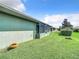 Landscaped backyard featuring green lawn and a portion of house exterior at 11111 Dormie Dr, San Antonio, FL 33576