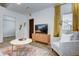 Bright living room features a comfy armchair, coffee table, and large TV at 963 Highland Ave, Dunedin, FL 34698