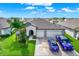 Two-car garage, driveway, and front yard with palm tree and landscaping at 13573 Willow Bluestar Loop, Riverview, FL 33579