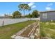 Large backyard with grassy area, some landscaping, and a white vinyl fence at 1009 Cobblestone Dr, Spring Hill, FL 34606
