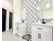 Contemporary bathroom featuring double vanities, marble counters, and geometric accent wall at 6710 Myrna Dr, Tampa, FL 33619