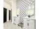Contemporary bathroom featuring double vanities, marble counters, and geometric accent wall at 6710 Myrna Dr, Tampa, FL 33619