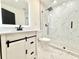 Bathroom features vanity with barn door style hardware and frameless glass shower with marble style tile at 6710 Myrna Dr, Tampa, FL 33619