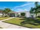 Single story home with stone and white exterior, palm trees, and a lush lawn at 5823 Dory Way, Tampa, FL 33615