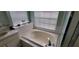 Bright bathroom featuring a soaking tub, tiled surround, and window with blinds at 4467 Worthington Ct, Palm Harbor, FL 34685