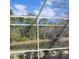 View of pond beyond the screened-in pool area with mature trees at 4467 Worthington Ct, Palm Harbor, FL 34685
