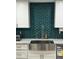 Close-up of a kitchen sink featuring emerald backsplash, modern faucet, and white cabinetry at 4810 Chancellor Ne St, St Petersburg, FL 33703
