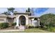 Tan two-story house with a three car garage and lush landscaping at 4467 Worthington Ct, Palm Harbor, FL 34685