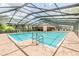 Community pool with screened enclosure and lounge chairs at 3399 Mermoor Dr # 207, Palm Harbor, FL 34685